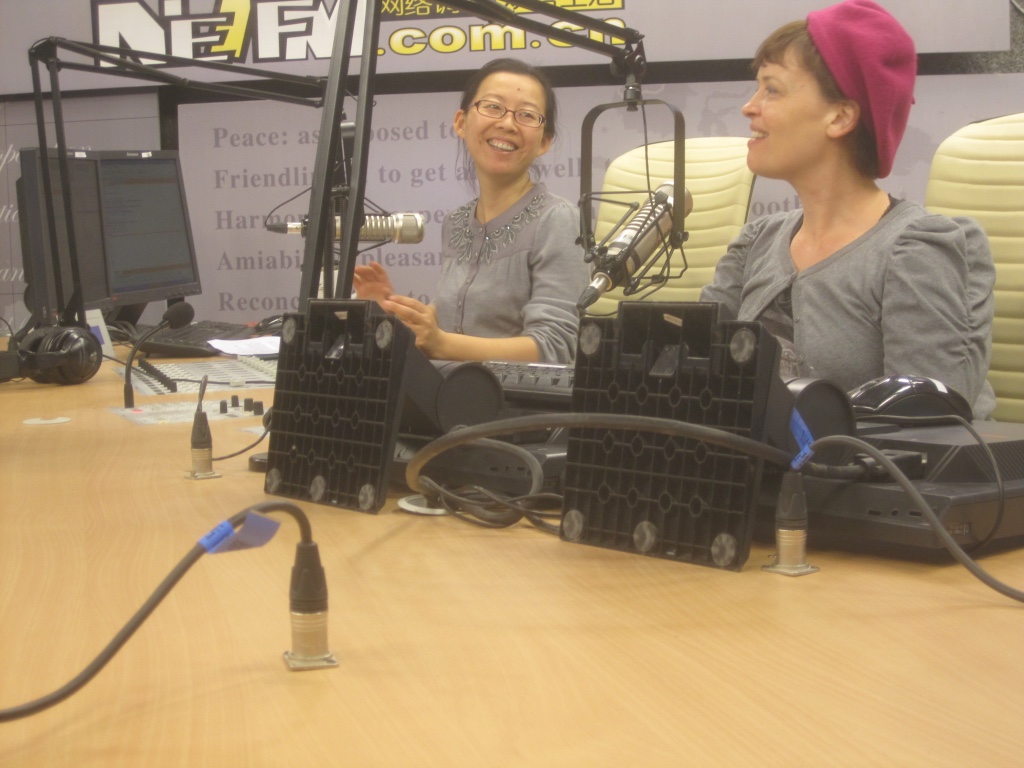 Bernadette in a radio studio being interviewed by a smiling Chinese journalist.