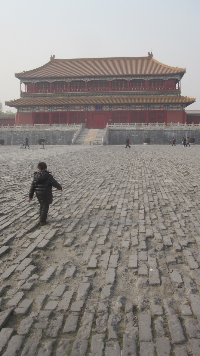 A small boy walks along in the forbidden city.