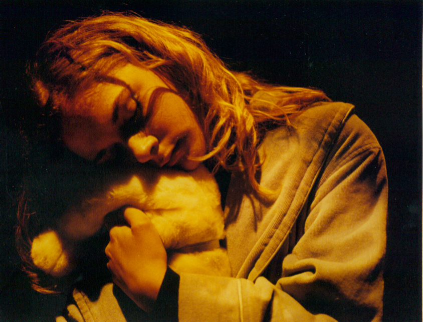 Young woman sleeps cuddling a teddy bear